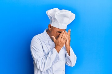 Mature middle east man wearing professional cook uniform and hat with sad expression covering face...