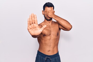 Fototapeta premium Young latin man standing shirtless covering eyes with hands and doing stop gesture with sad and fear expression. embarrassed and negative concept.