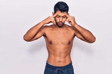 Fototapeta premium Young latin man standing shirtless with hand on head for pain in head because stress. suffering migraine.