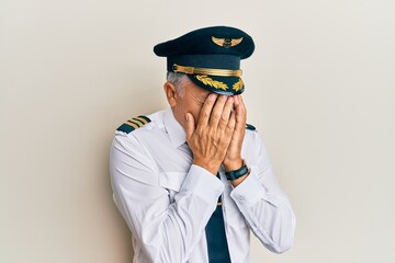 Handsome middle age mature man wearing airplane pilot uniform with sad expression covering face...