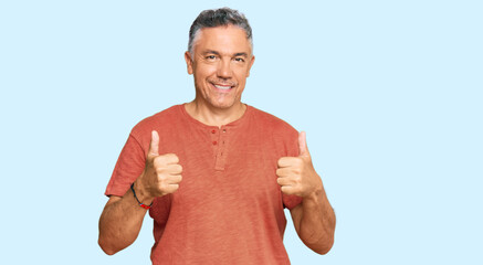 Handsome middle age man wearing casual clothes success sign doing positive gesture with hand, thumbs up smiling and happy. cheerful expression and winner gesture.