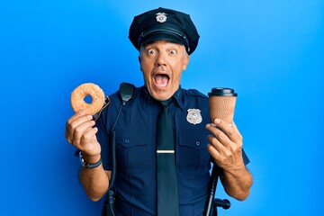 Handsome middle age mature police man eating donut and drinking coffee celebrating crazy and amazed...