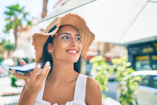 Young latin girl wearing summer style talking on the smartphone at street of city.