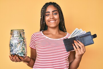 Young african american woman with braids with savings jar and wallet with dollars smiling with a...