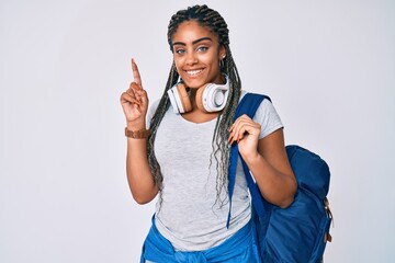 Young african american woman with braids wearing student backpack and headphones surprised with an idea or question pointing finger with happy face, number one