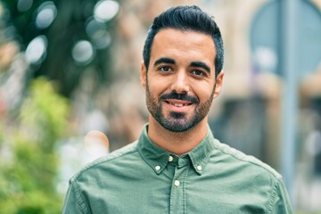 Naklejka premium Young hispanic man smiling happy standing at the city.