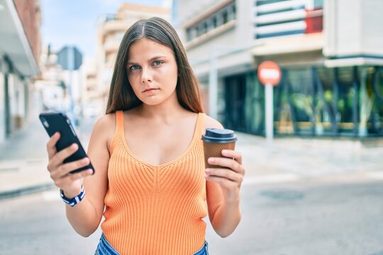 Young middle east gir with serious expression using smartphone and drinking coffee at the city.