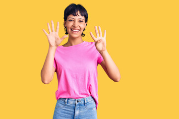 Young brunette woman with short hair wearing casual clothes showing and pointing up with fingers...