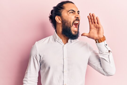 Young arab man wearing casual clothes shouting and screaming loud to side with hand on mouth. communication concept.