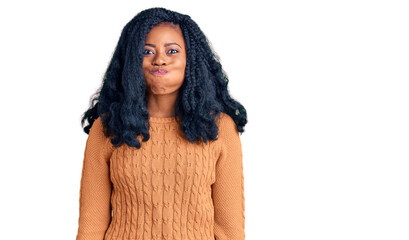 Beautiful african american woman wearing casual  sweater puffing cheeks with funny face. mouth inflated with air, crazy expression.