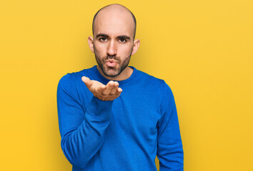 Young hispanic man wearing casual clothes looking at the camera blowing a kiss with hand on air being lovely and sexy. love expression.