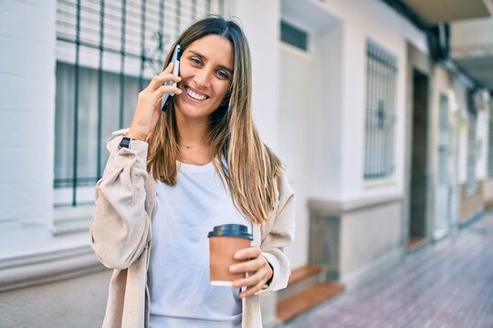 Young caucasian woman smiling happy talking on the smartphone and drinking take away coffee at the city.