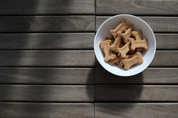 dry dog food in a bowl on wooden background top view