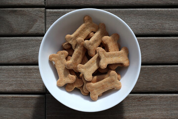 dry dog food in a bowl on wooden background top view