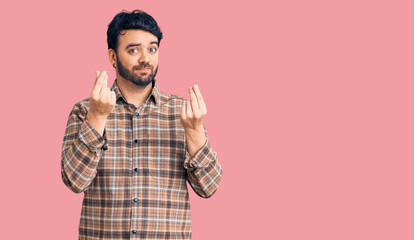 Young hispanic man wearing casual clothes doing money gesture with hands, asking for salary...