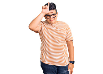 Fototapeta premium Little boy kid wearing casual clothes and glasses making fun of people with fingers on forehead doing loser gesture mocking and insulting.