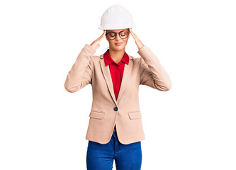 Young beautiful woman wearing architect hardhat suffering from headache desperate and stressed because pain and migraine. hands on head.