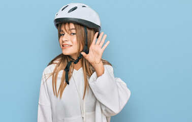 Teenager caucasian girl wearing bike helmet smiling with hand over ear listening an hearing to rumor or gossip. deafness concept.
