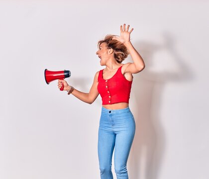 Young beautiful caucasian woman screaming using megaphone. Jumping over isolated white background
