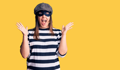 Young beautiful brunette woman wearing burglar mask celebrating crazy and amazed for success with...