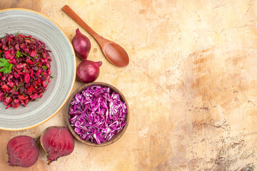 Fototapeta na wymiar top view salad on gray plate with green leaves mix vegetables with red onions beetroots and chopped cabbage on a wooden table with free space