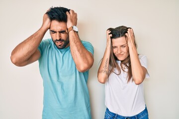 Beautiful young couple of boyfriend and girlfriend together suffering from headache desperate and stressed because pain and migraine. hands on head.