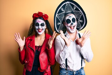 Fototapeta na wymiar Couple wearing day of the dead costume over yellow celebrating mad and crazy for success with arms raised and closed eyes screaming excited. winner concept