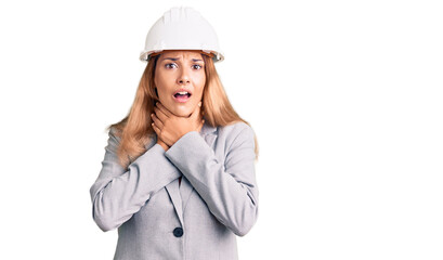 Beautiful young woman wearing architect hardhat shouting and suffocate because painful strangle. health problem. asphyxiate and suicide concept.