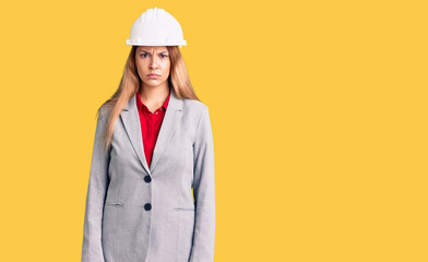 Beautiful young woman wearing architect hardhat skeptic and nervous, frowning upset because of...