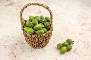 Top view of fresh feijoa a small green vitamin bomb inside and outside of a basket on white background