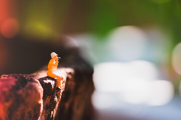 Miniature people, woman sitting on blurry background using for holiday concept