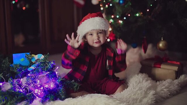 a child in red clothes is sitting waiting for the new year. the concept of celebrating Christmas at midnight. holiday costume