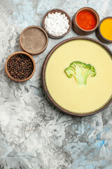 Creamy broccoli soup in a brown bowl and different spices on gray background stock image