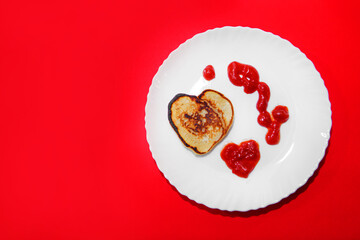 pancakes and ketchup in the shape of a heart on February 14. food for Valentine's day on a red background.