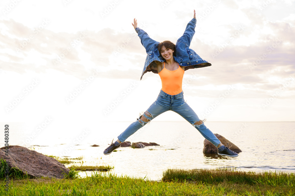 Wall mural girl jumping at sunset against the background of the sea