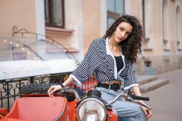 Fototapeta na wymiar Young woman sits on a motorcycle outdoors.