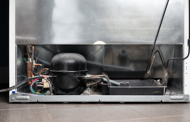 Back of the Refrigerator. View of fridge backside with compressor condenser, corroded copper pipes and electrical wiring. Lots of dust and pet hair. Concept for maintaining and repair appliances. - obrazy, fototapety, plakaty