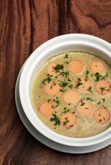 German traditional KARTOFFELSUPPE potato and sausage soup on wood table