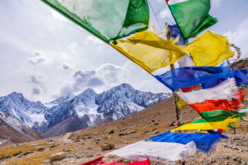 Colorful prayer flags flying in winds with Himalayas mountains at Kunzum pass which connects Lahaul valley and Spiti valley from Manali in Himachal Pradesh.