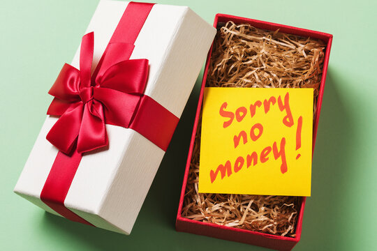 Open gift box with a note inside on a green background. Concept on the topic of lack of money for gifts