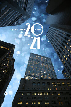 Fototapeta Happy New 2021 year text in beautiful winter snowfall sky seen through city skyscrapers skyline in downtown Manhattan, New York.