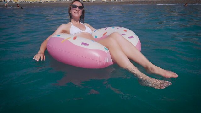 A beautiful woman in bekini rests on the sea. A young woman in sunglasses, swims on an inflatable circle.