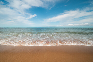 Wave on sand beach with blue sky