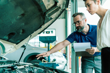 An auto mechanic talking to female customer in garage