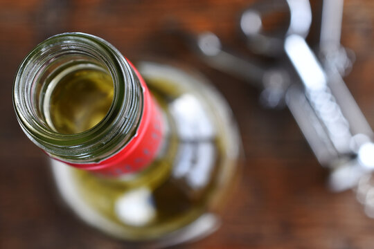 A top view image of an open bottle of wine with a silver bottle opener. 