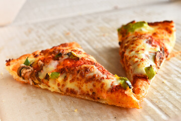 An image of two slices of leftover pieces of pizza in a carboard delivery box.  