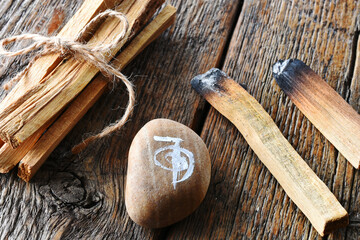 A close up image of several smudge sticks and healing reiki symbol on a dark wooden table. 