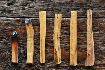 A close up image of of several pieces of burnt Holy wood incense on a dark wooden table.  