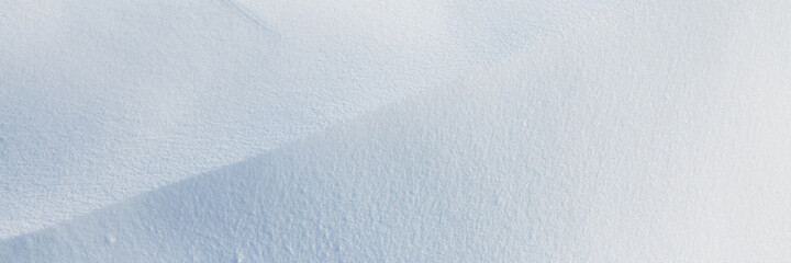 Beautiful winter background with snowy ground. Natural snow texture. Wind sculpted patterns on snow surface. Wide panoramic texture for background and design.