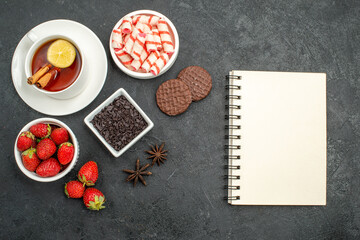 Fototapeta na wymiar top view fresh strawberries with sweets and tea on the dark background photo sweet cracker